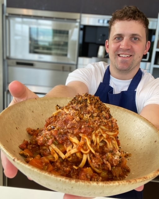 Chef Jon Watts holding a bowl of Spaghetti Bolognese