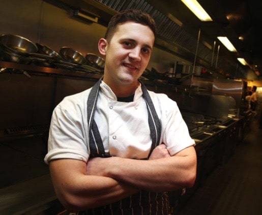 Chef Jon Watts standing in a restaurantl kitchen