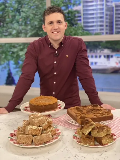 Chef Jon Watts standing behind freshly baked cakes on ITV This Morning