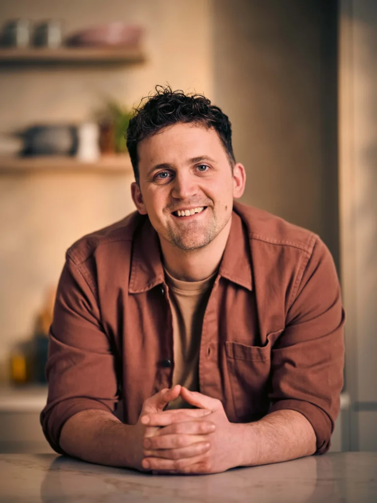 Jon Watts smiling in a kitchen